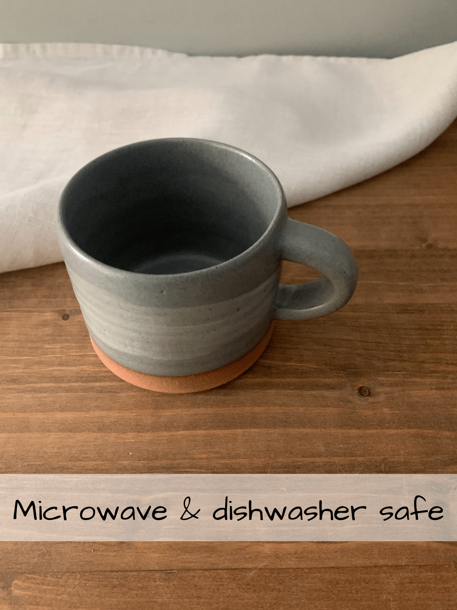 Gray ceramic mug on a wooden surface with text indicating safety features.
