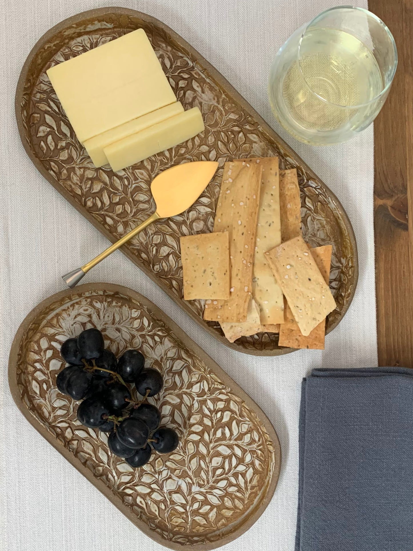 handcrafted Decorative ceramic platters with cheese, crackers, and grapes on a white surface.