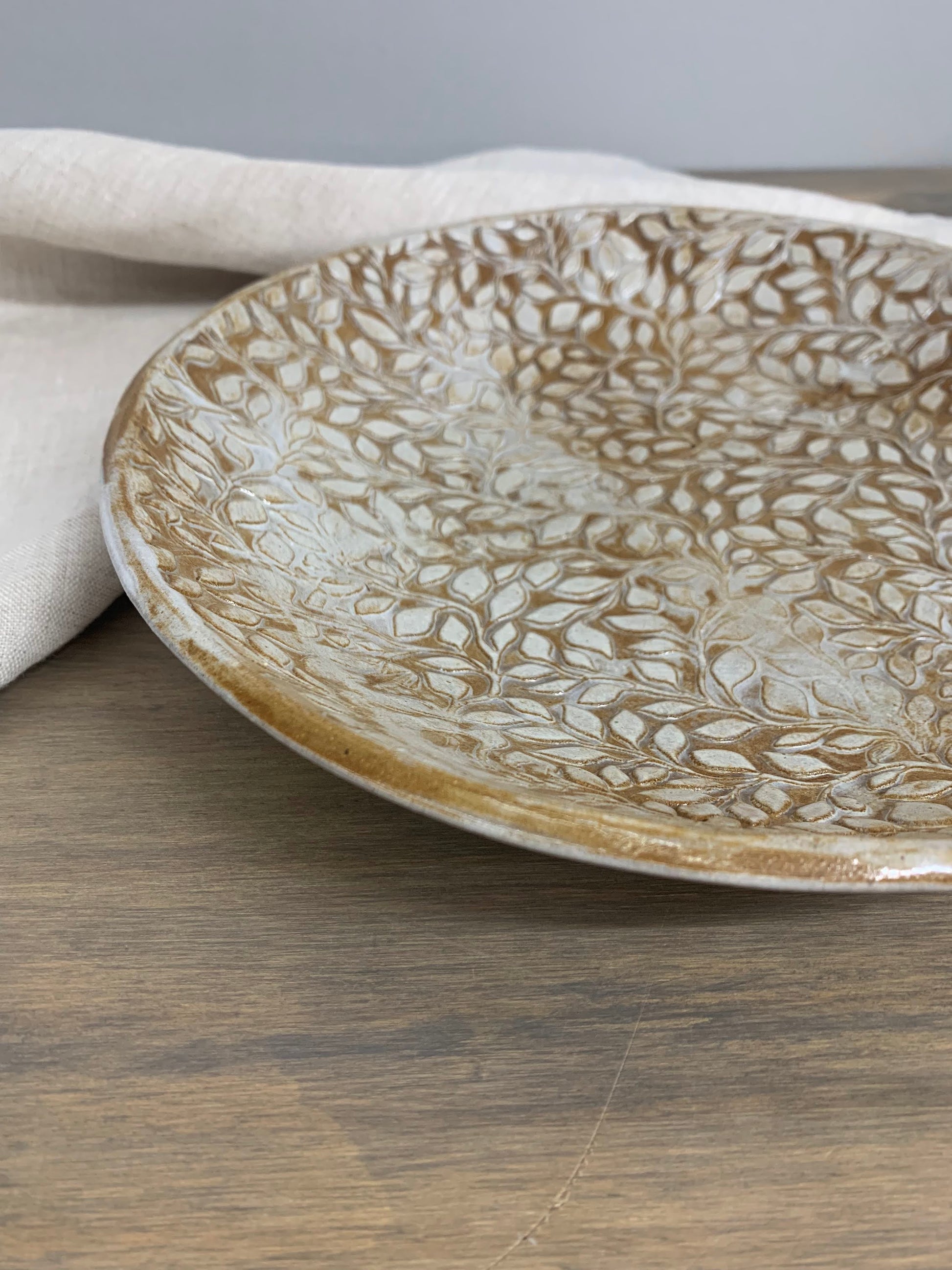 Decorative handcrafted ceramic bowl with leaf pattern on a wooden surface