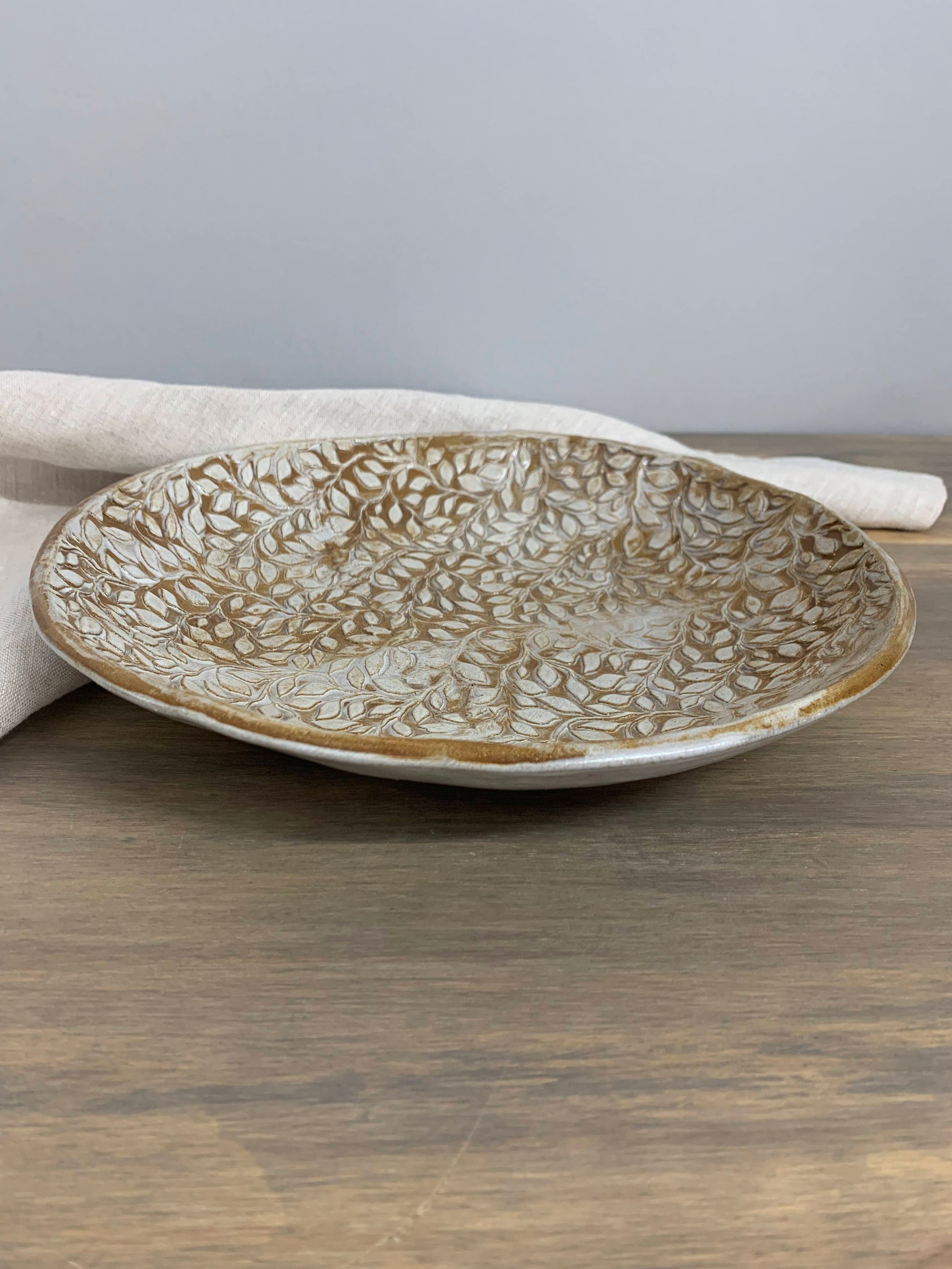 Decorative ceramic shallow fruit bowl with textured design on a wooden surface
