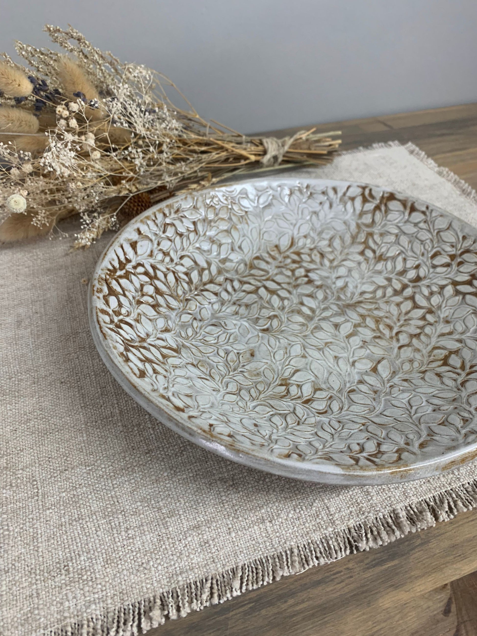 Decorative handcrafted ceramic bowl with intricate leaf patterns on a textured surface